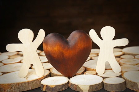 Brown heart with two figures on wood logsの写真素材