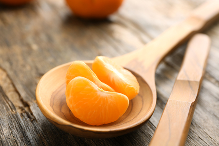 Peeled slices of fresh, delicious tangerine on the rustic table, close upの写真素材