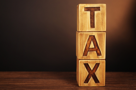 Word TAX written on wooden cubes on dark backgroundの写真素材