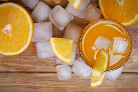Orange juice with cubes of ice and orange on wooden table background, closeupの写真素材