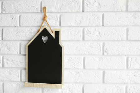 House shaped chalkboard hanging on brick wall, closeupの写真素材