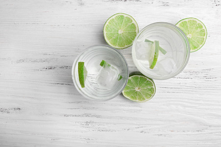 Fresh cocktails with ice and lime on white wooden table background, view from aboveの写真素材