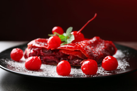 Powdered cherry strudel with mint on dark red backgroundの写真素材