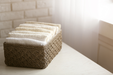 Wicker basket with towels inside on wooden table backgroundの写真素材