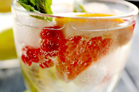 Refreshing cocktail with ice, mint, pomegranate seeds and slices of fruitsの写真素材