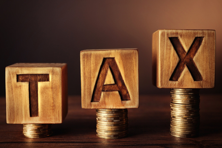 Word tax with stacked coins on dark backgroundの写真素材