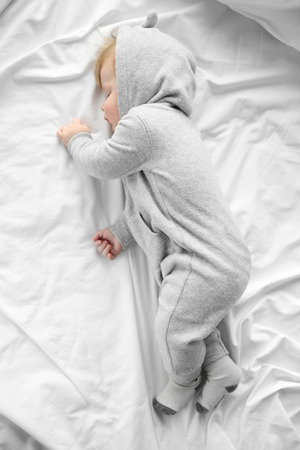 Little baby boy in grey pajamas sleeping on the bedの写真素材