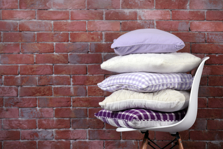 Few pillows on chair against brick wall backgroundの写真素材
