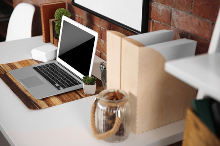 Workplace with laptop and table on brick wall backgroundの写真素材
