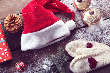 Christmas Santa hat with a gift box and decorations on a wooden tableの写真素材