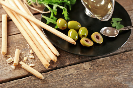 Bread sticks with arugula, oil and olives on plateの写真素材