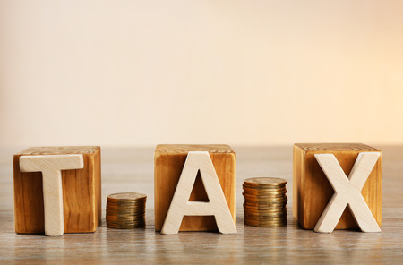 Tax concept with wooden blocks and coins on tableの写真素材