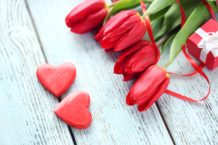 Red tulips bouquet with a gift box on a light-blue tableの写真素材