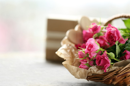 Pink roses in a wicker basket on a white table, close upの写真素材