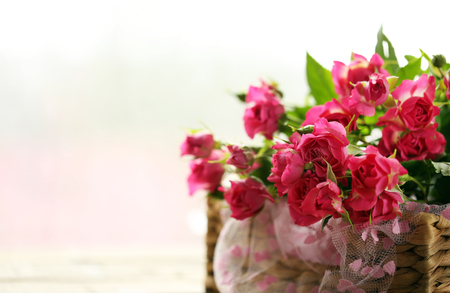 Pink roses in a wicker basket on a table, close upの写真素材