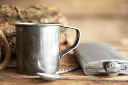 Metal mug of coffee with flask, spoon and rope on wooden backgroundの写真素材
