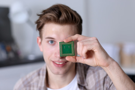 Young man holding computer processor near eyeの写真素材