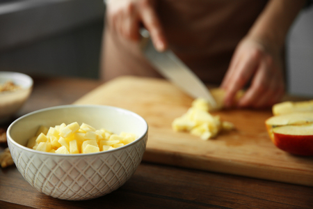Woman chopping ripe apple on a cutting boardの写真素材