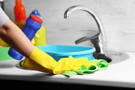 Female hands with rag and detergent bottle cleaning a sink in the kitchenの写真素材