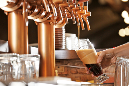Barman hand pouring a lager beer in a glass.の写真素材