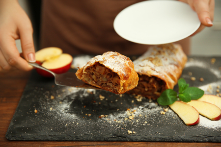 Woman putting a piece of apple roll on saucerの写真素材