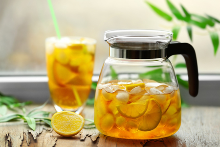 Glass and jar of iced tea with lemon on a windowsillの写真素材