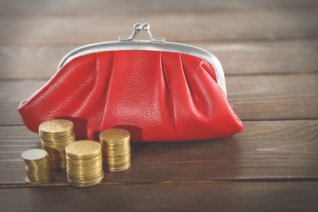 Red leather purse and stacked coins on wooden backgroundの写真素材