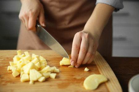 Woman chopping ripe apple on a cutting board