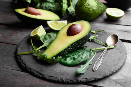 Sliced avocado with lime, spinach and arugula on slate plate