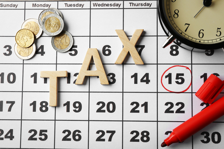 Tax time and alarm clock with coins, marker and calendarの写真素材