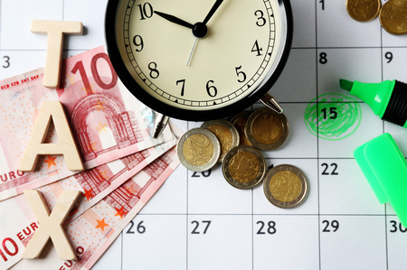 Tax time and alarm clock with money, marker and calendarの写真素材
