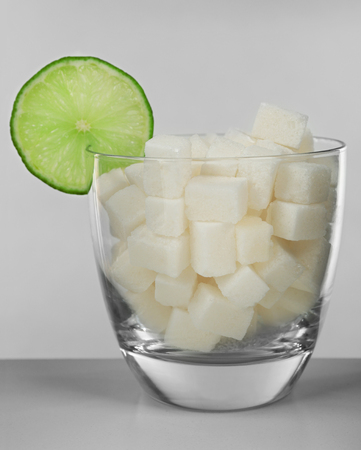 Glass full of sugar with lime on grey backgroundの写真素材