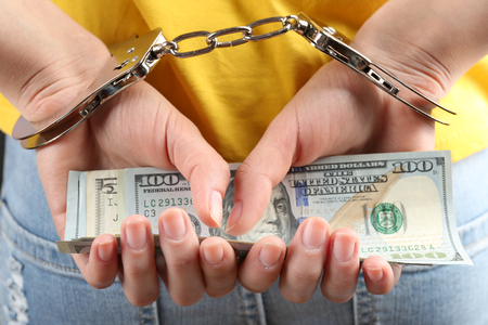Hands in handcuffs behind back holding dollar banknotes, close up. Corruption conceptの写真素材