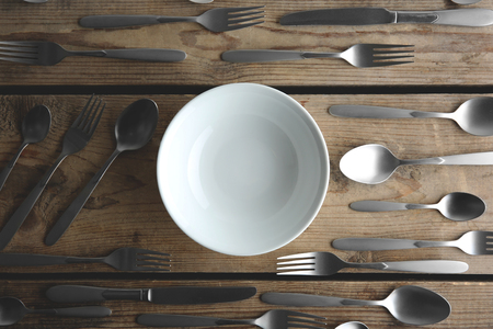 Plate and silver cutlery on wooden table, top viewの写真素材