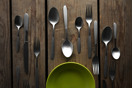 Plate and silver cutlery on wooden table, top viewの写真素材