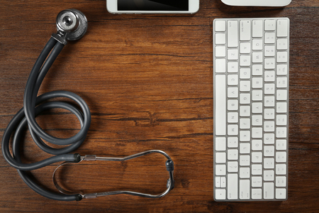 Tablet, phone, keyboard and stethoscope on the table, top viewの写真素材