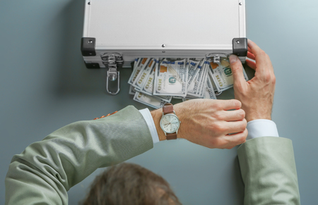 Businessman with case full of money on grey backgroundの写真素材