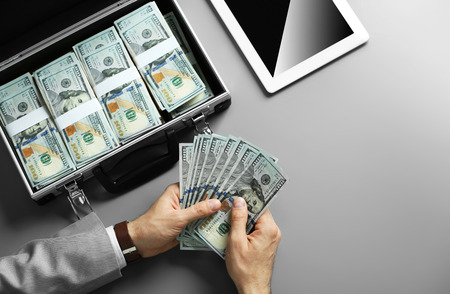 Businessman counting money on grey background