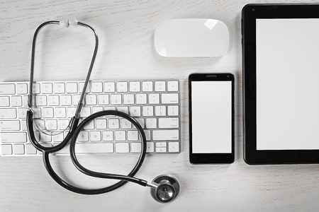 Tablet, phone, keyboard and stethoscope on the table, top viewの写真素材