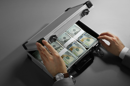 Businessman with case full of money on grey backgroundの写真素材