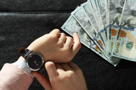 Businesswoman with watch and brief case full of money moneyの写真素材