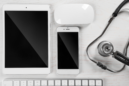 Tablet, phone, keyboard and stethoscope on the table, top viewの写真素材