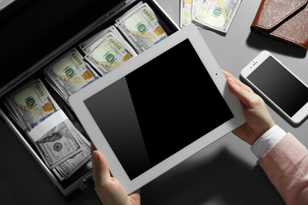 Businesswoman with tablet and case full of moneyの写真素材