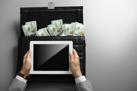 Businessman with tablet and brief case full of money moneyの写真素材