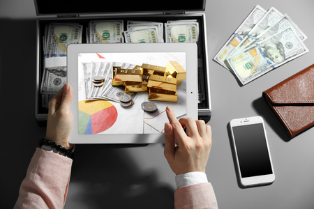 Businesswoman with tablet and case full of moneyの写真素材