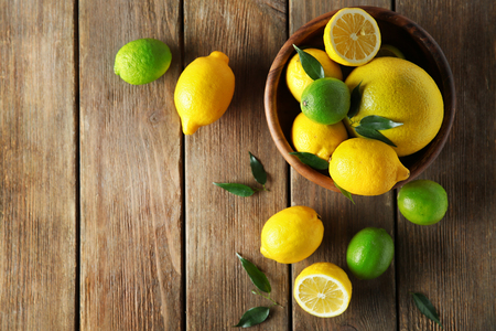 Fresh citrus fruits in a bowl on a wooden table.の写真素材