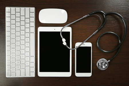 Tablet, phone, keyboard and stethoscope on the table, top viewの写真素材
