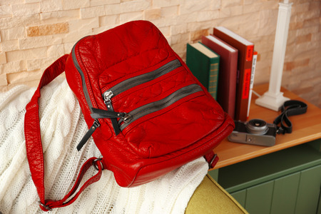 Red leather backpack on the green couch.の写真素材