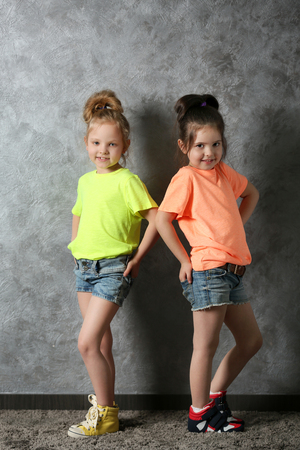 Two stylish little girls on wall backgroundの写真素材