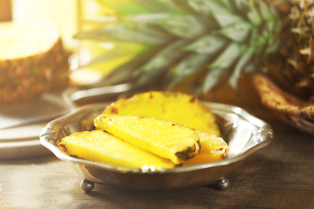 Juicy pineapple slices in silver plate on wooden tableの写真素材